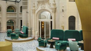 A lobby with green upholstered seating, a round gold table, and a marble floor. - W Budapest (Budapest)