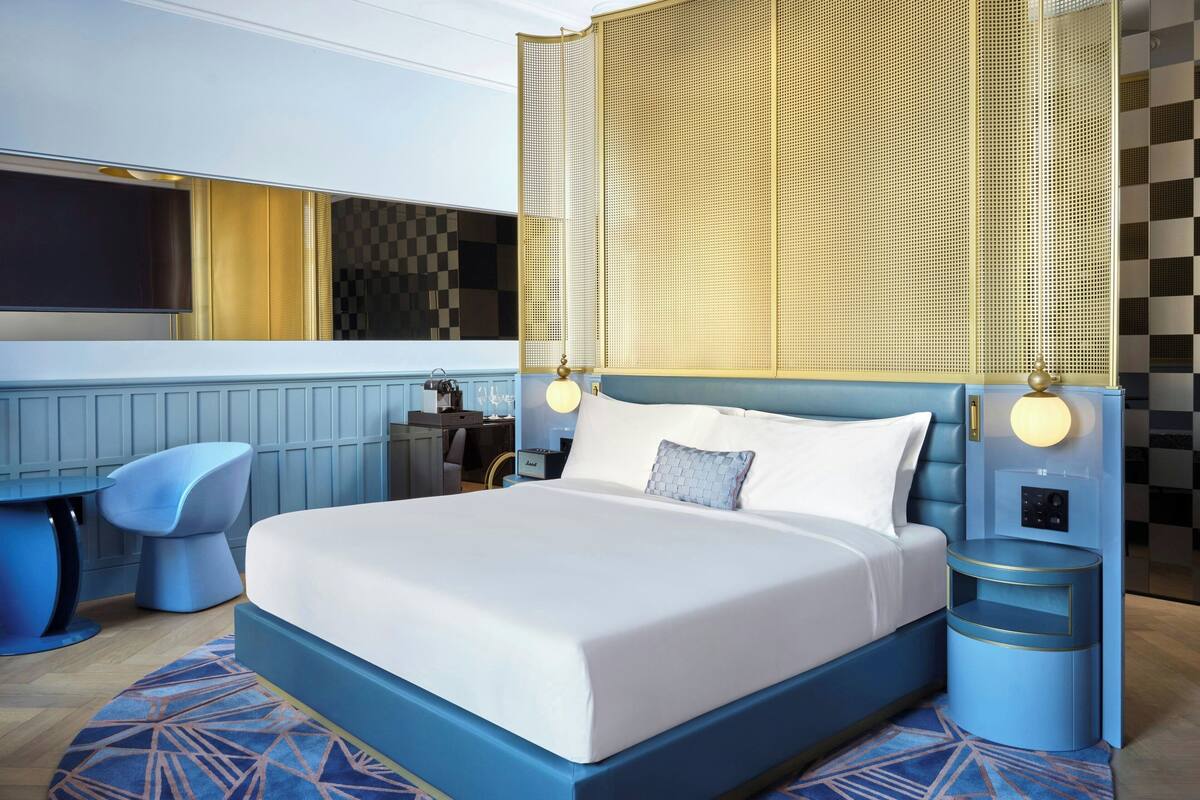 A modern hotel room with a large bed, a desk, and a chair.