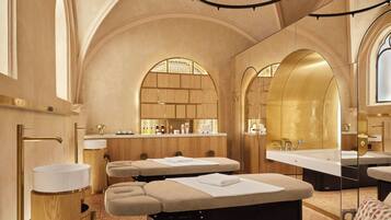 A luxurious spa room with wooden cabinetry, a large mirror, and a central massage table.