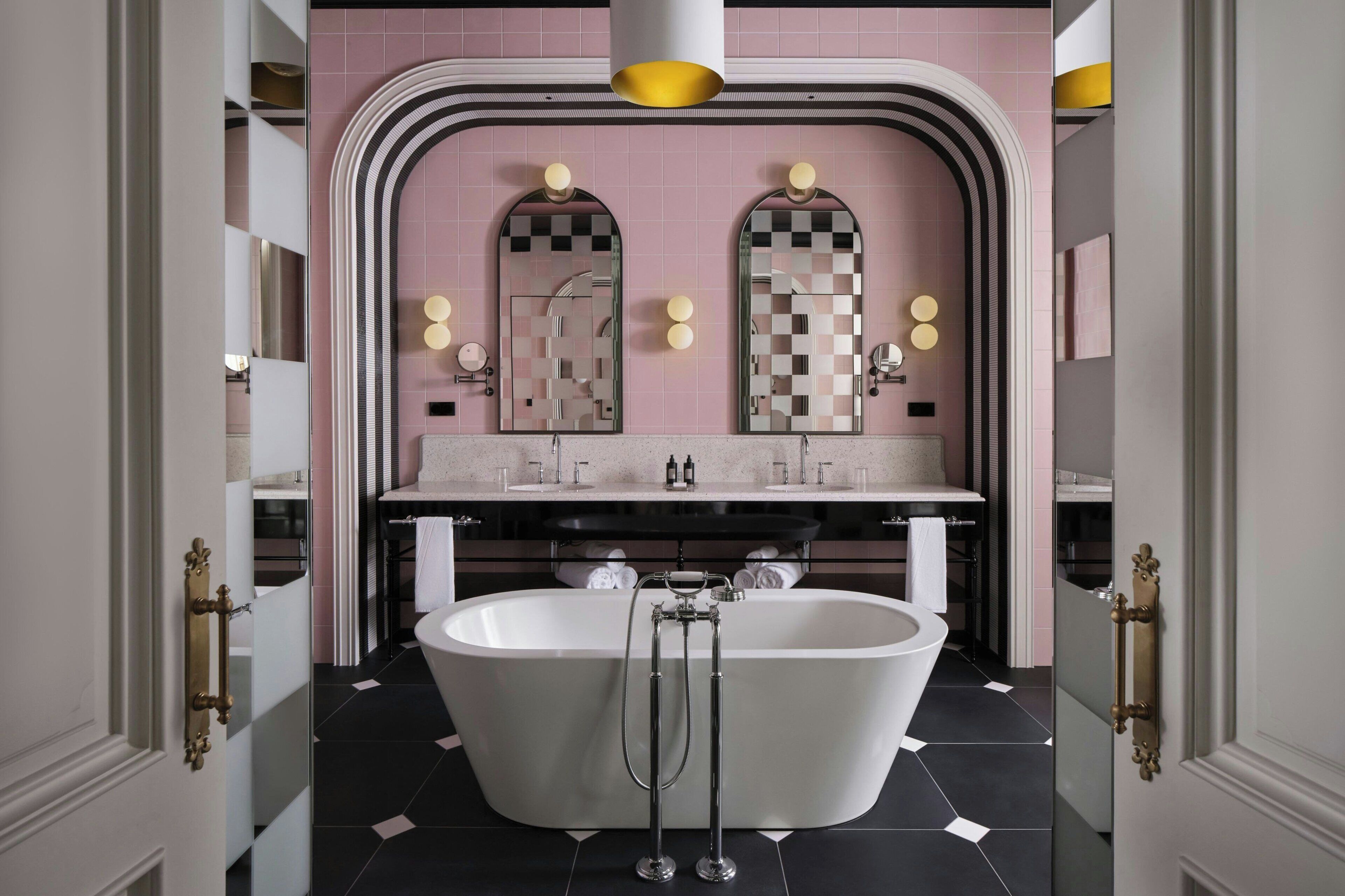 A modern bathroom with a freestanding bathtub, a vanity with a mirror, and a large mirror above the sink.