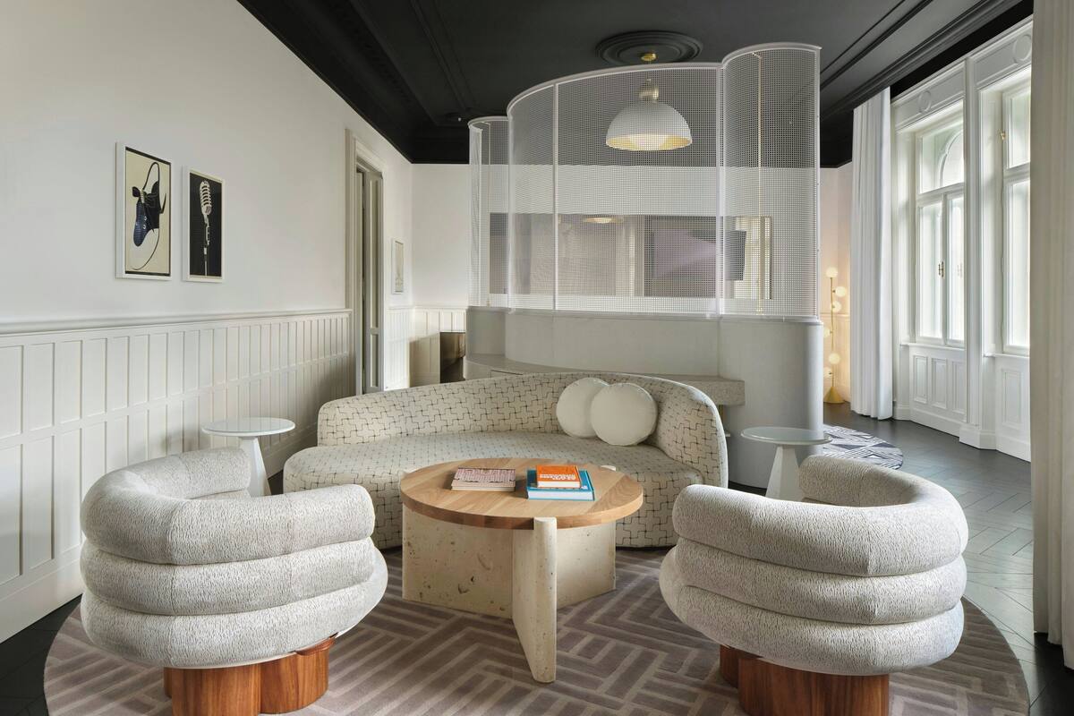 A modern living room with a sofa, two armchairs, a coffee table, and a unique hanging light fixture.