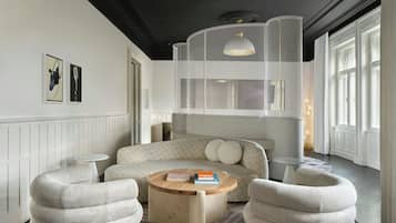Una sala de estar moderna con un sofá, dos sillones, una mesita de centro y una lámpara colgante original.