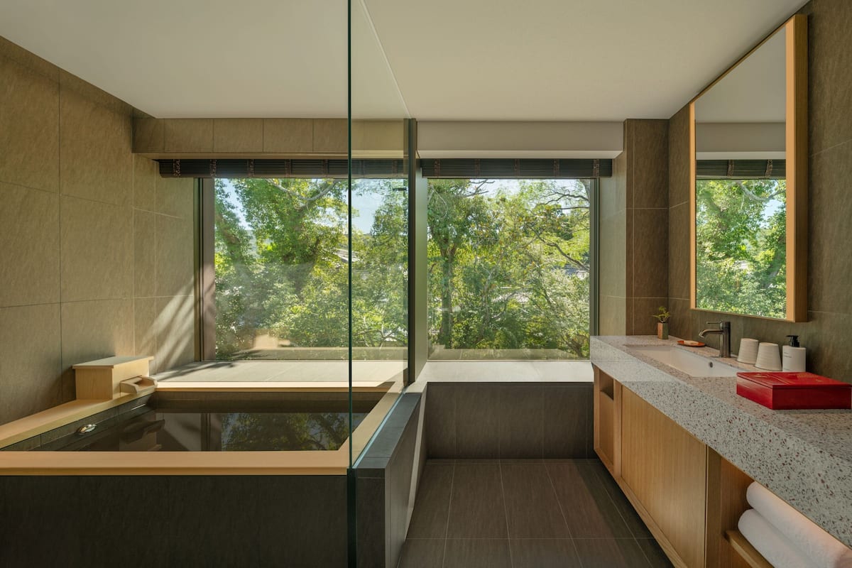 Un baño moderno con un ventanal grande, una bañera y un lavabo con espejo.