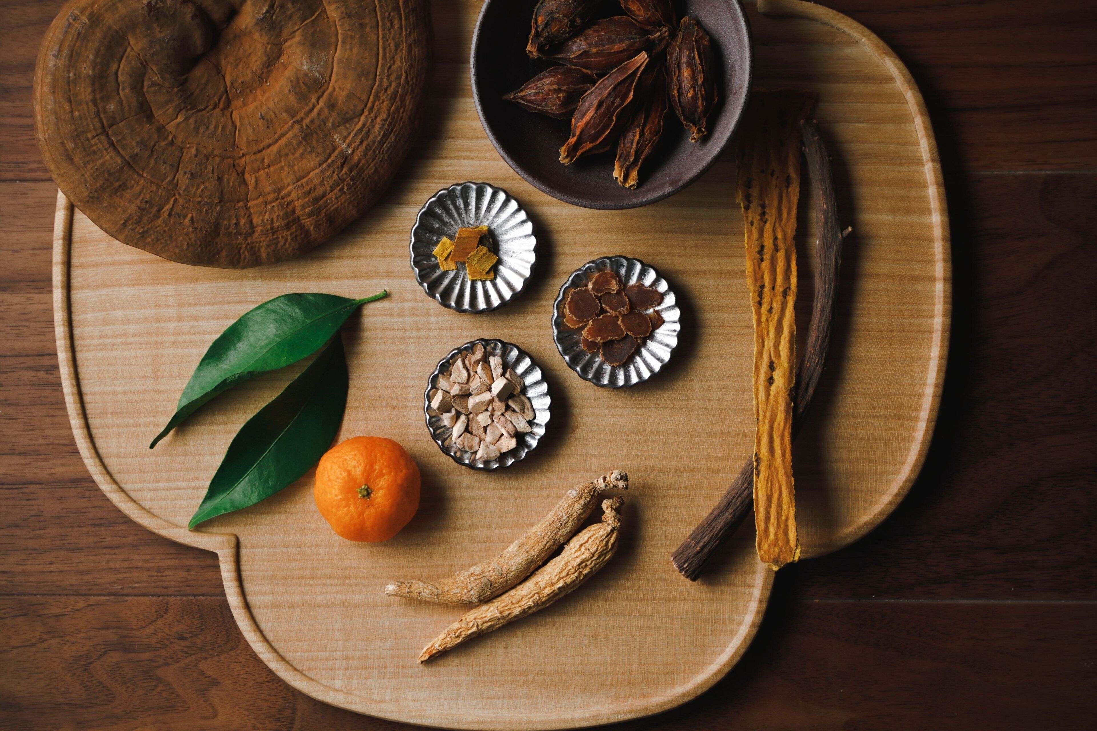 A wooden tray with various dried spices and a cinnamon stick.