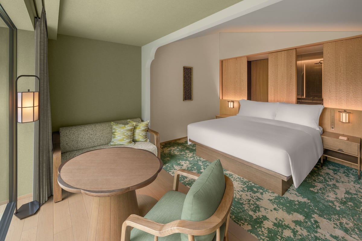 Una habitación de hotel con una cama, un sofá, una mesa redonda y un espejo.