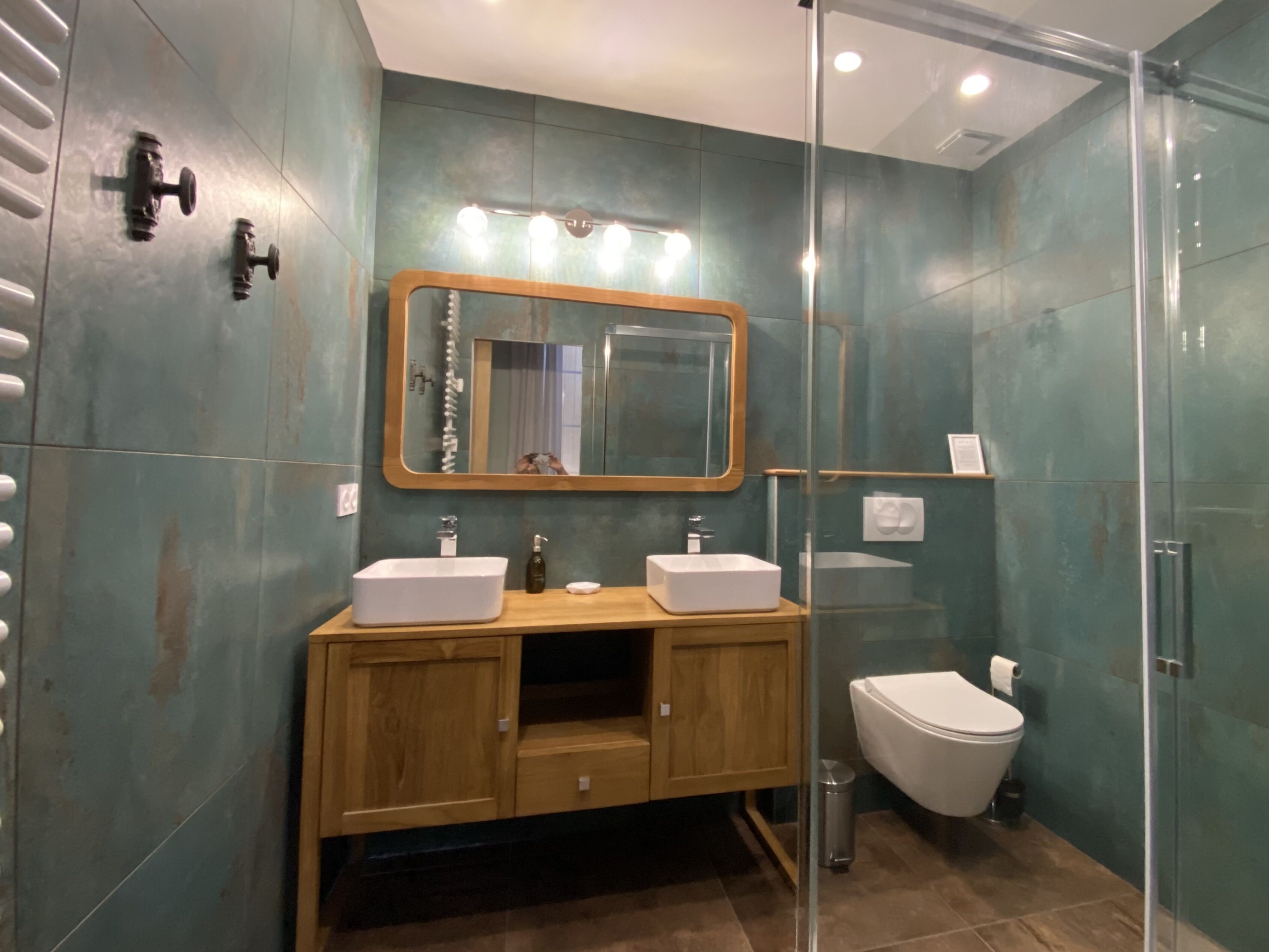 Un baño moderno con dos lavamanos, un espejo y una cabina de ducha de vidrio.