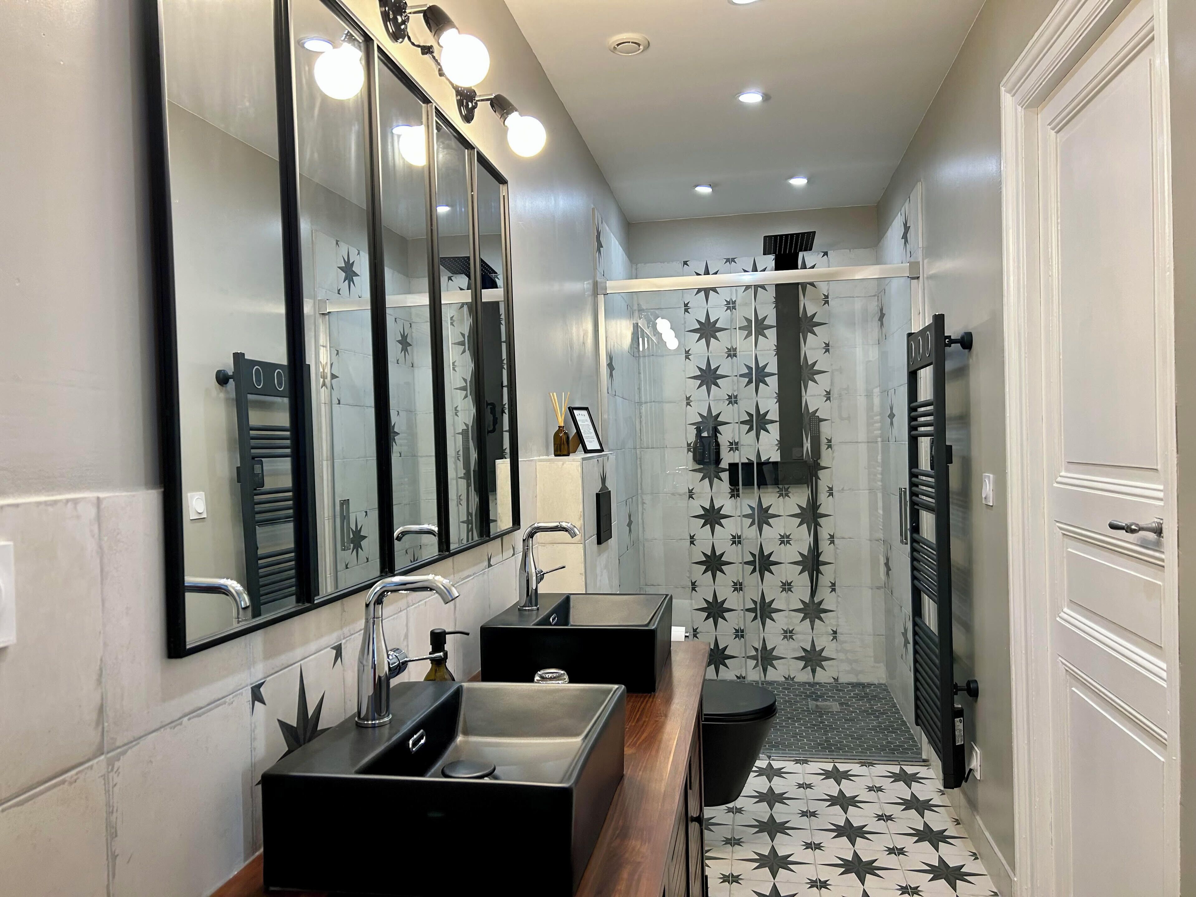 Un baño moderno con dos lavamanos, un espejo grande y una zona de ducha.