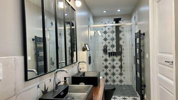 Un baño moderno con dos lavamanos, un espejo grande y una zona de ducha.