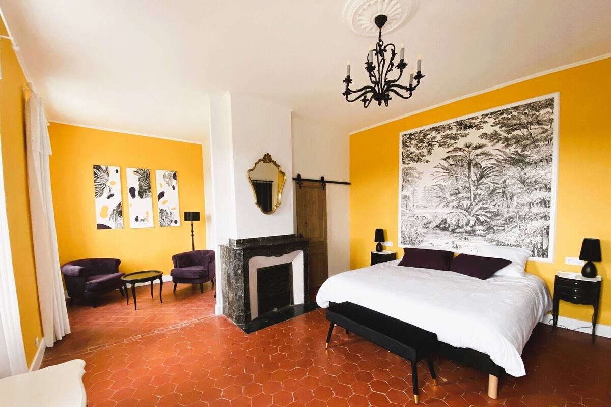 Un dormitorio con una cama grande, una chimenea y un tapiz mural de gran tamaño.