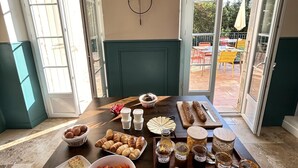 A breakfast buffet with various food items and condiments on a table in a room with large windows and a view of the outdoors.