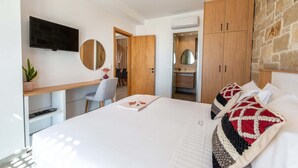 Une chambre moderne avec un lit, un bureau, une télévision et un mur en pierre.