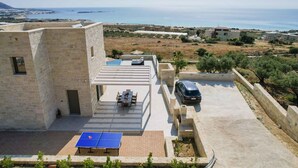 Une terrasse sur le toit avec une table de ping-pong, un espace salon couvert et une vue sur la mer.