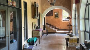 A spacious hallway with a tiled floor, a chandelier, and a staircase leading to an upper level.