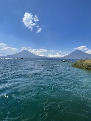 Une vue dégagée sur une mer calme, avec des bateaux, une montagne à l’horizon et un ciel clair.