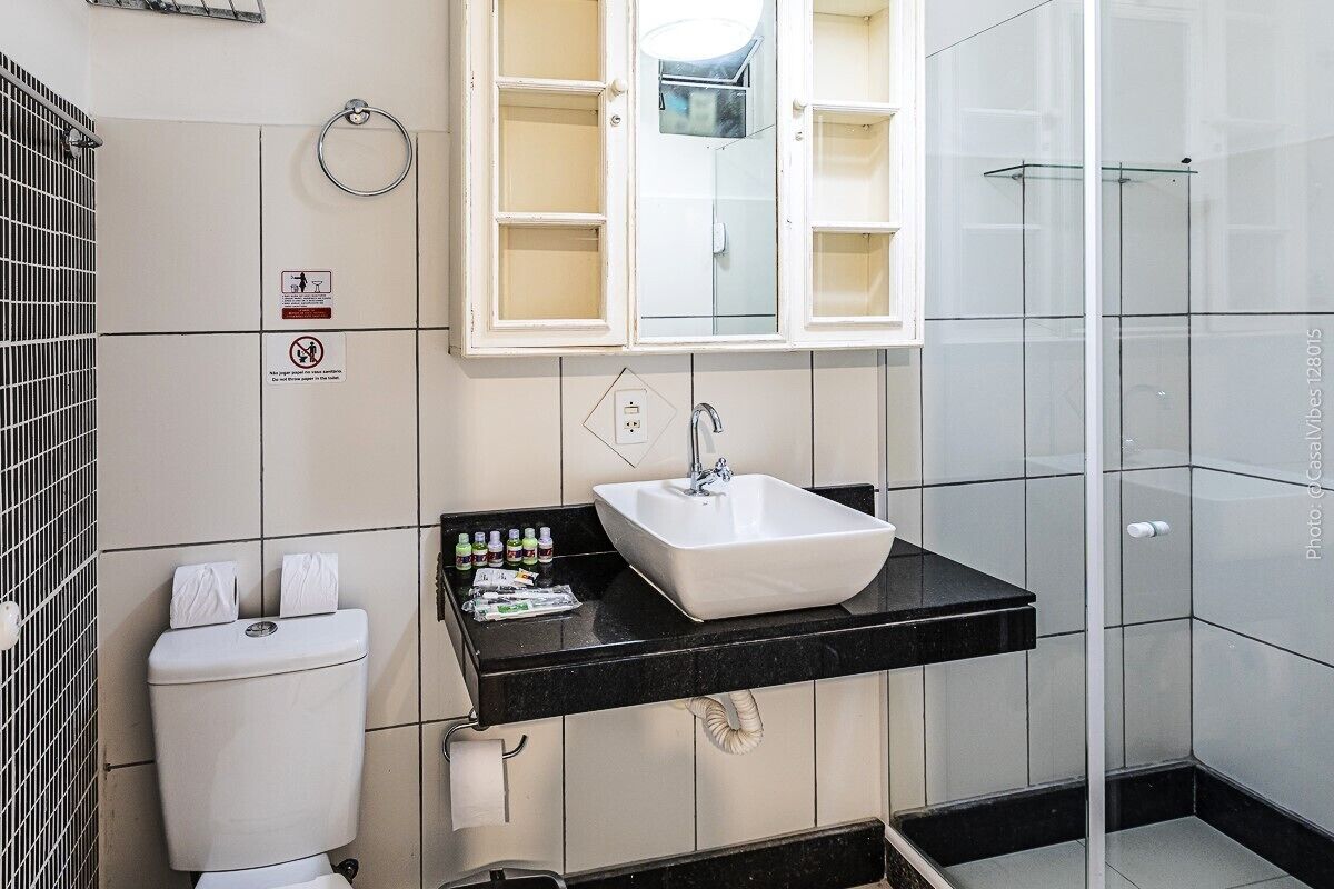 A bathroom with a white toilet, a black sink, and a glass shower enclosure.
