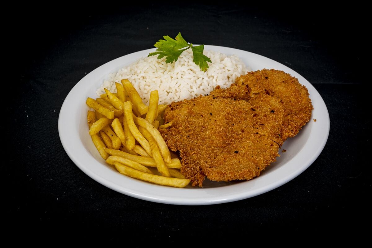Une assiette composée d’une escalope panée, de frites et de riz blanc.