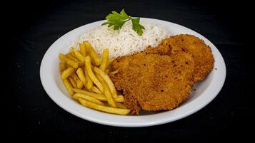 Une assiette composée d’une escalope panée, de frites et de riz blanc.