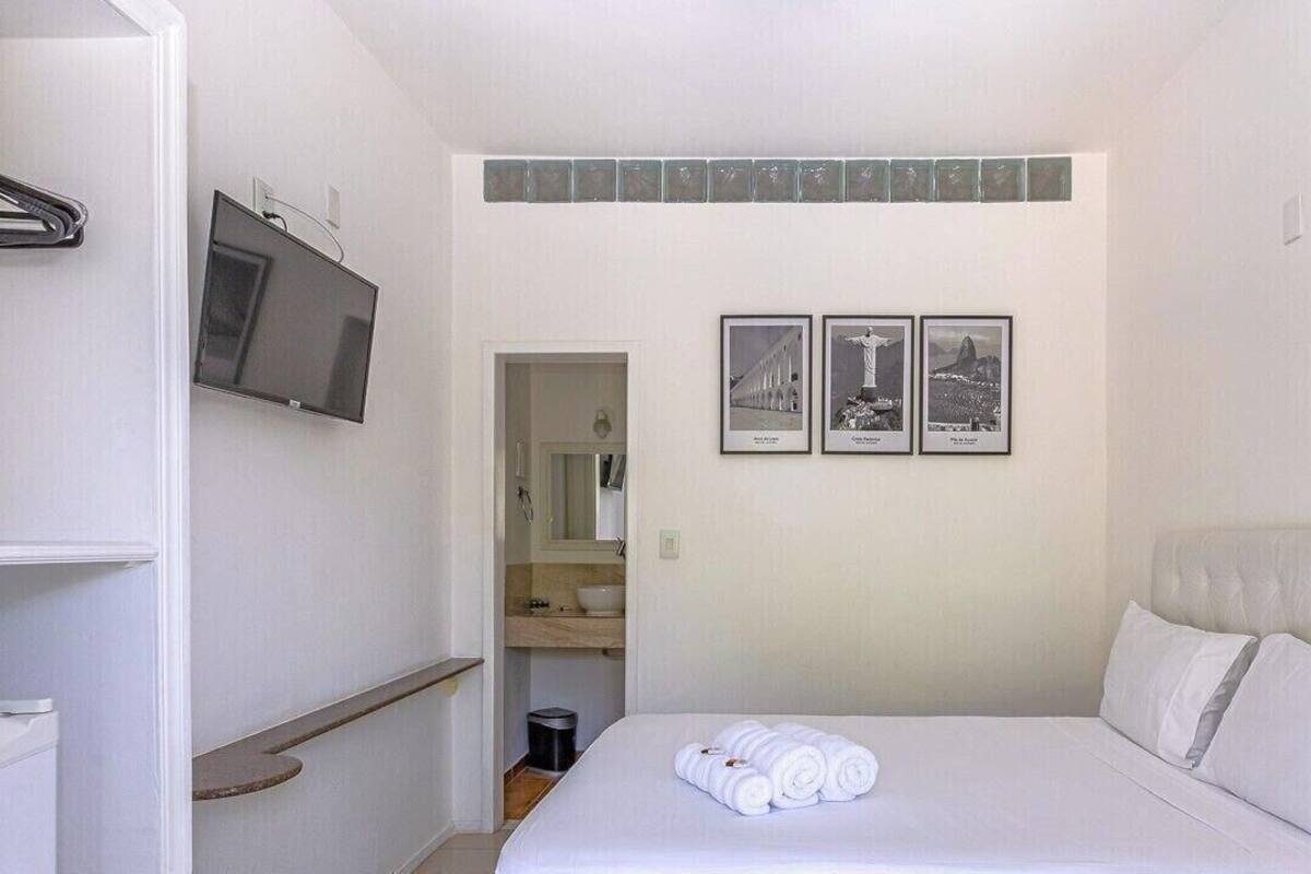 Une chambre à coucher avec un lit, une télévision, une étagère et trois tableaux encadrés accrochés au mur.