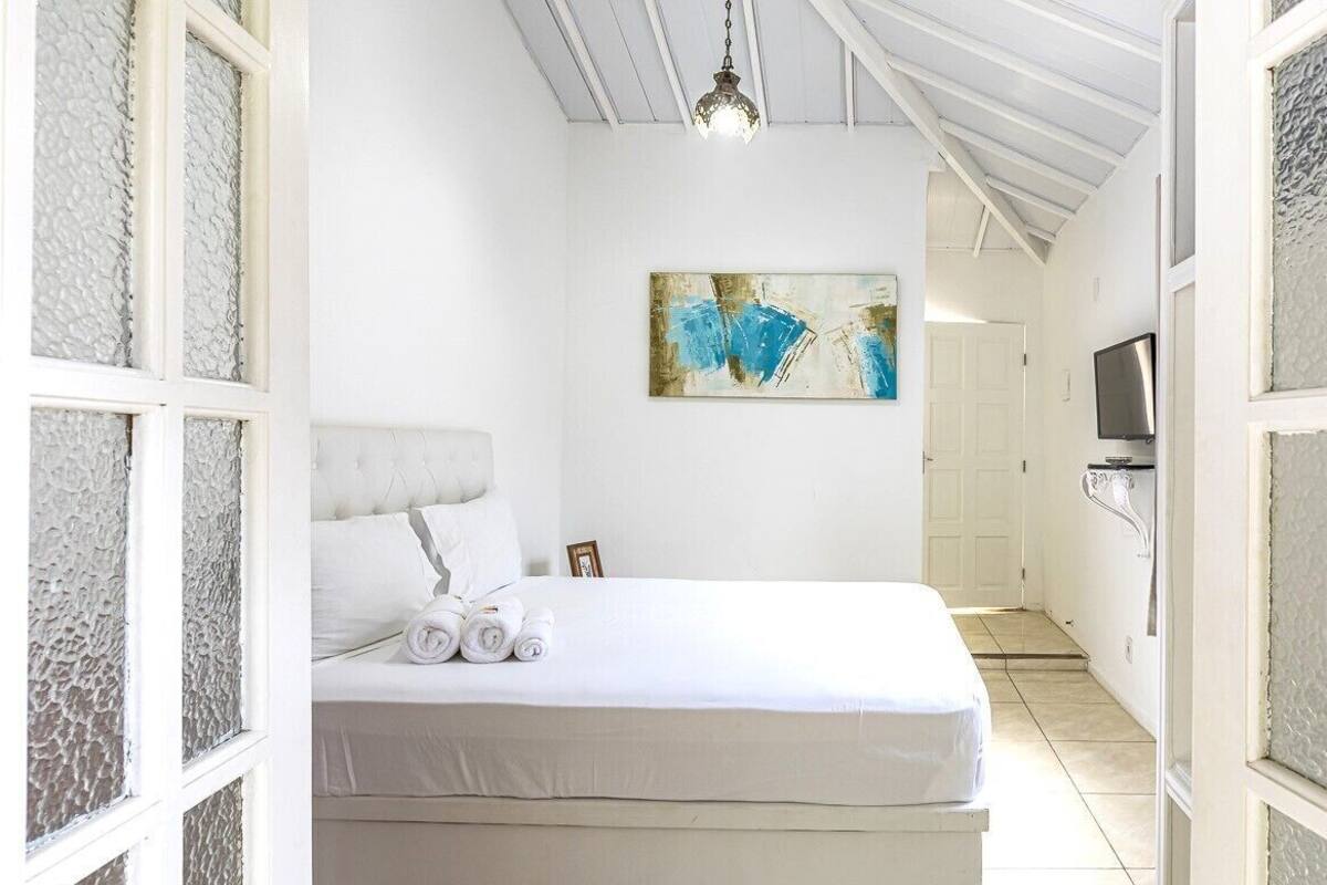 Une chambre à coucher avec un lit, un tableau, une télévision et un couloir.