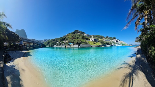 A coastal scene with a clear blue sea, a sandy beach, and a bridge. - RioZin Pousada Liberal - Adults Only - Clothing Optional (Rio de Janeiro)