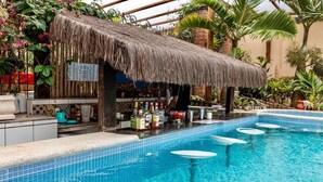 A pool area with a bar, a thatched-roof structure, and tropical plants. - RioZin Pousada Liberal - Adults Only - Clothing Optional (Rio de Janeiro)