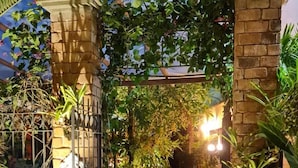 A nighttime garden with a pool, stone walls, and various plants. - RioZin Pousada Liberal - Adults Only - Clothing Optional (Rio de Janeiro)