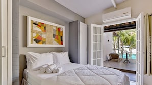 A hotel room with a large bed, a painting on the wall, and an open door leading to a pool area. - RioZin Pousada Liberal - Adults Only - Clothing Optional (Rio de Janeiro)