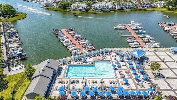 A marina with boats docked, a swimming pool, and lounge areas with umbrellas. - Cozy house in Ocean pines, only 10 mins away from Ocean City. (Ocean Pines)