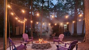 A fire pit surrounded by Adirondack chairs in a backyard with string lights. - Cozy house in Ocean pines, only 10 mins away from Ocean City. (Ocean Pines)