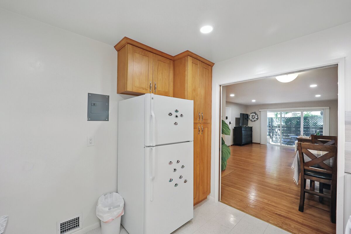 A kitchen with wooden cabinets, a white refrigerator, and a dining area with a table and chairs.