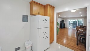 Een keuken met houten kastjes, een witte koelkast en een eethoek met een tafel en stoelen.