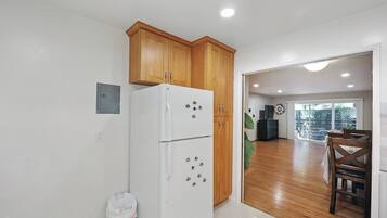 A kitchen with wooden cabinets, a white refrigerator, and a dining area with a table and chairs.