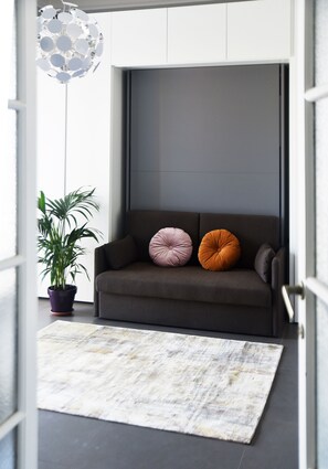 Relax in this stylish living space with a sofa, potted plant, and unique light fixture.