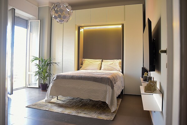 Relax in this serene bedroom with a large bed, a potted plant, and a flat-screen TV.
