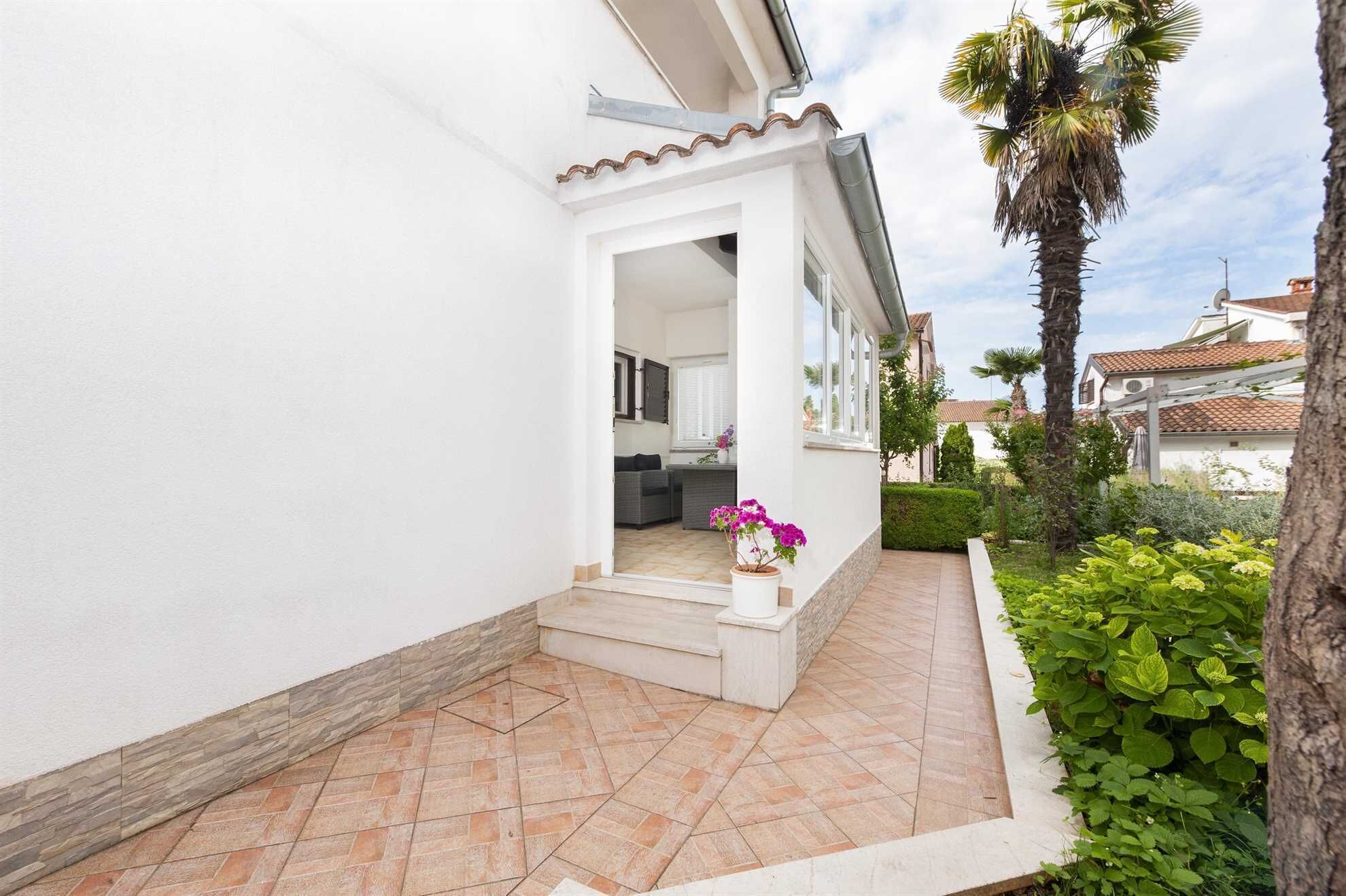 A white house with a tiled patio and a small garden.