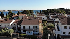 Un quartier résidentiel situé sur la côte, caractérisé par des toits recouverts de tuiles en terre cuite, des murs blancs et une vue dégagée sur la mer.