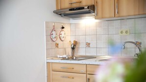 A kitchen with wooden cabinets, a stainless steel range hood, a tiled backsplash, and a sink with a faucet.