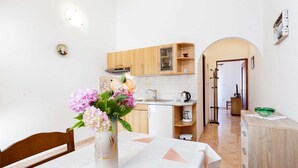 A modern kitchen with wooden cabinets, a white countertop, and a vase of flowers.