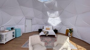 A spacious tent with a bed, two armchairs, a small table, and a microwave. - Capitol Reef Dome | Oak (Wayne County)