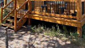 Eine Blockhütte mit Holzterrasse, einer Treppe und einem Essbereich mit Gartenmöbeln.