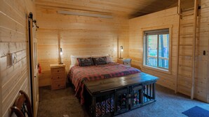 A cozy log cabin bedroom with a bed, bedside tables, a bench, a window, and a ladder. - Mini Moose-28 Miles to Yellowstone-Owner Operated (Island Park)