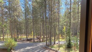 Eine Holzterrasse führt zu einem Kiesparkplatz mit Blick auf einen Wald.