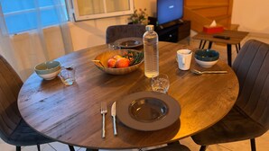Ett matbord dukat med en skål med frukt, en vattenflaska, en mugg och bestick.