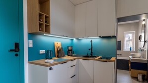 Una cocina compacta con armarios blancos, una encimera de madera y una pared azul decorativa.
