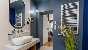 Un baño moderno con un lavamanos blanco, un espejo y un perchero para toallas.