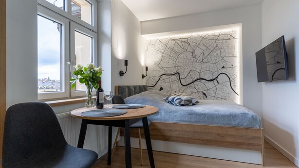 Un dormitorio moderno con cama, una mesa de comedor con sillas, un florero con flores y un mapa en la pared.