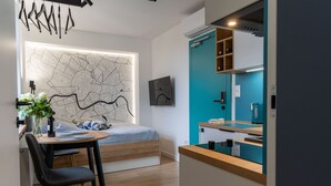 Un dormitorio moderno con cama, escritorio y silla. Hay un mapa en la pared, una planta y una ventana.