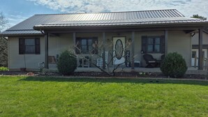 A single-story house with a metal roof, a front porch, and a welcome sign. -  Songbird Haven, 3 min from town, Pumpkinvine, MEC,concerts. 3 bedroom, 2 bath.  (Shipshewana)