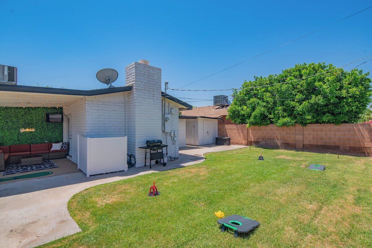 Un giardino con un'area barbecue, un caminetto in mattoni e un muro verde.