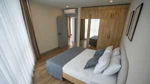 A bedroom with a bed, a wardrobe, and a window with curtains. - Let'stay Marine Homes (Antalya)